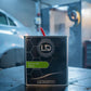 Lack Depot Express 600 hardener in a 2.5L metal container with a black carbon-fiber design in a professional workshop.